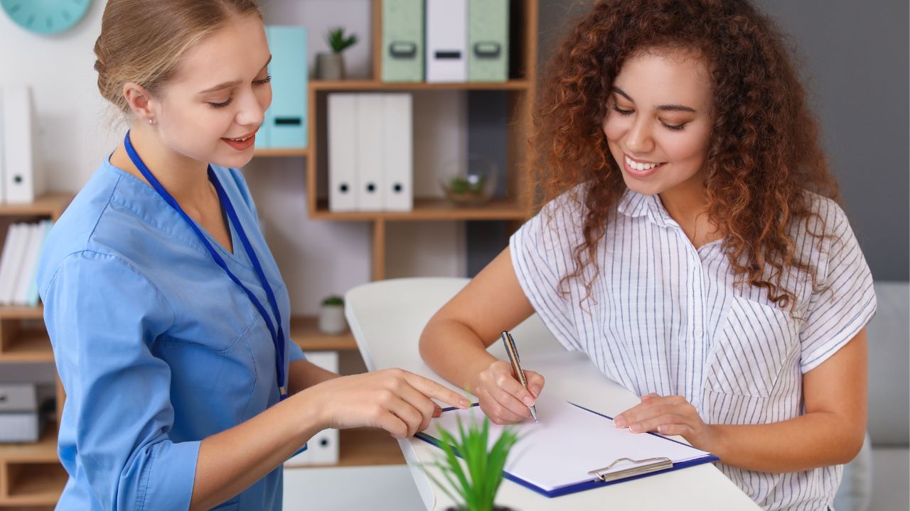 patient checking in to a clinic front counter, looking at paperwork