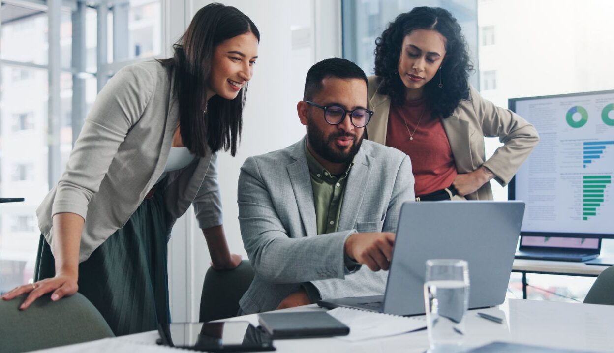 three administrative workers around a computer