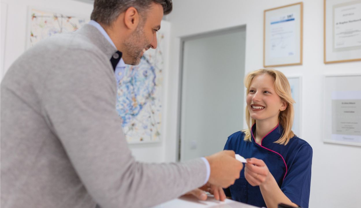 patient handing credit card to front counter receptionist