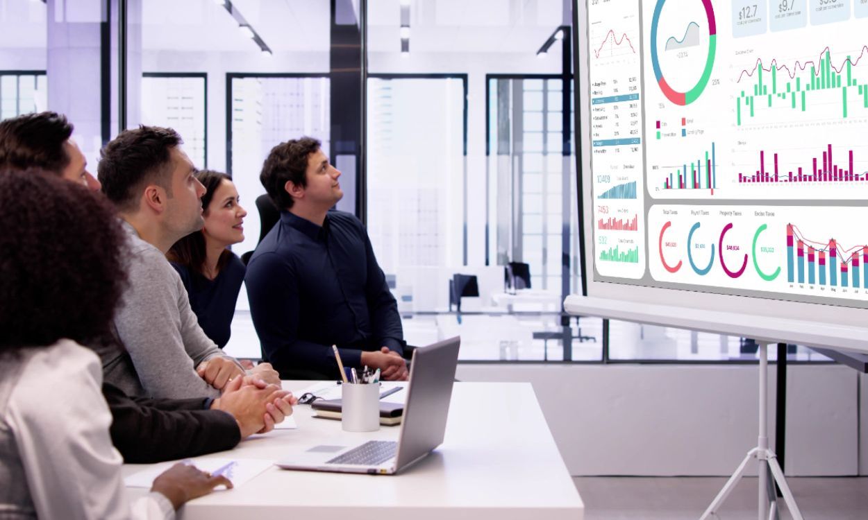 group of business people looking at large screen of financial information