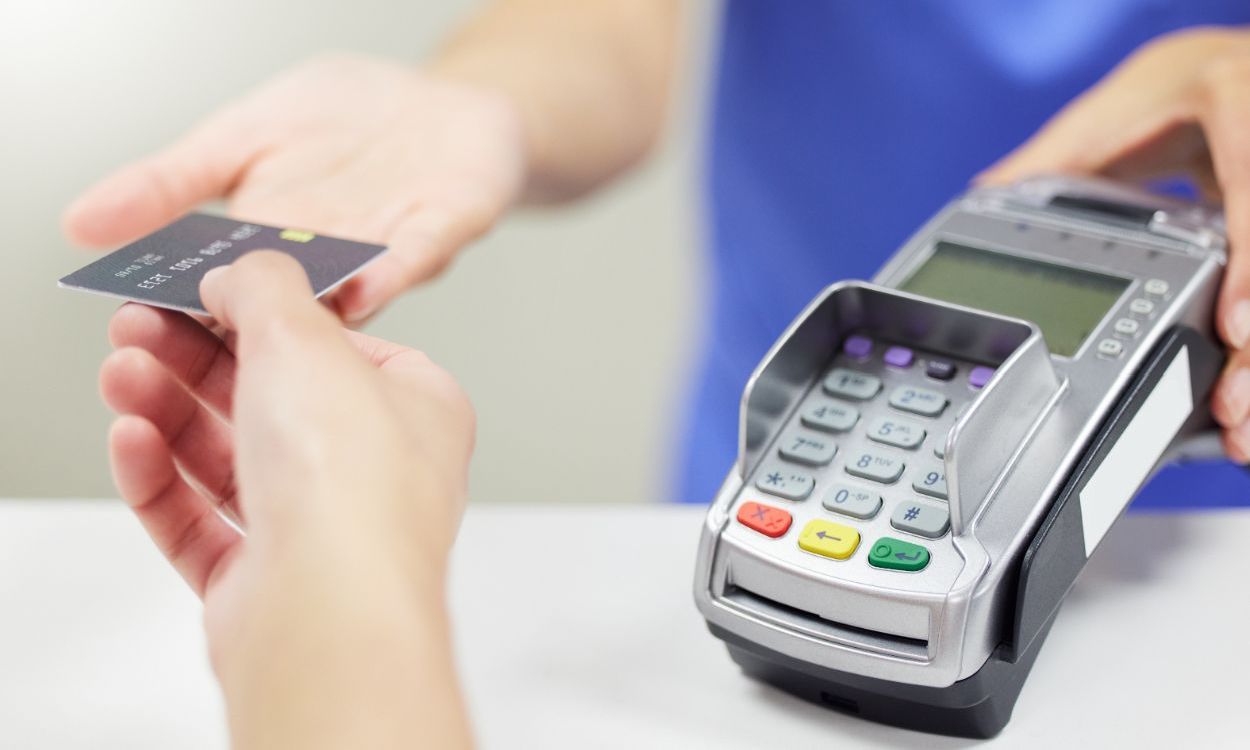 person handing credit card to receptionist at clinic counter