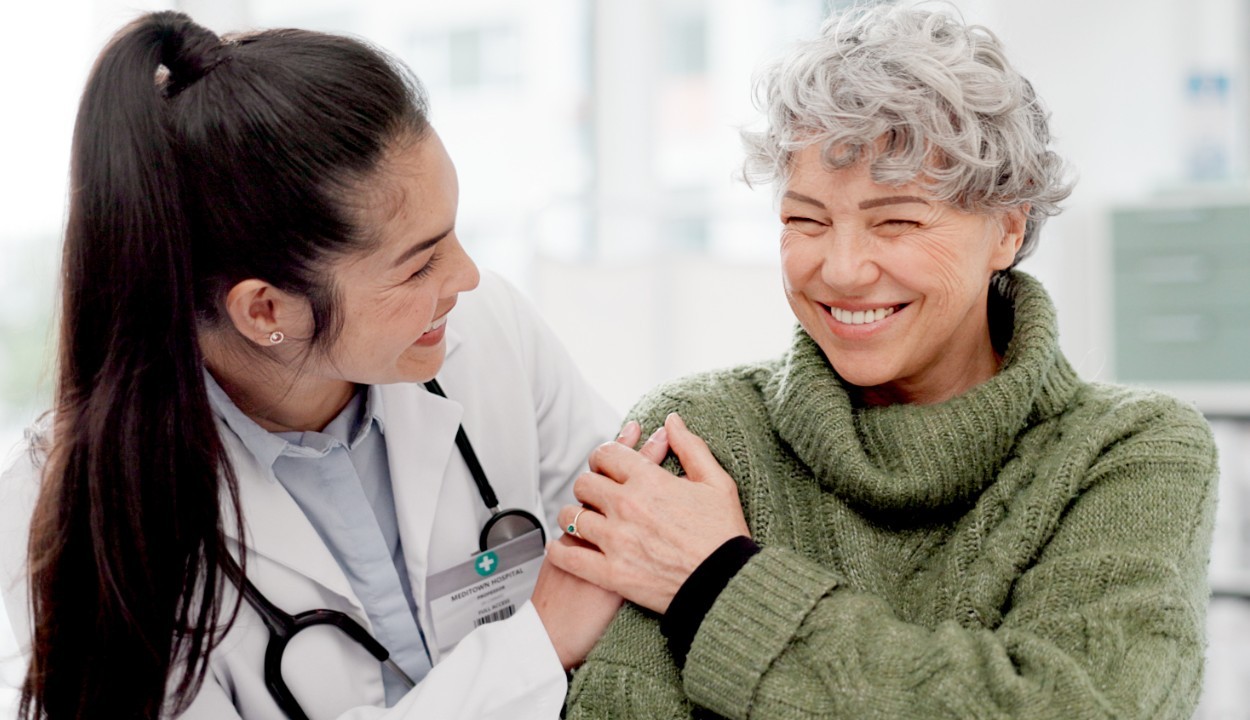 female physician with hand on the shoulder of a smiling patient