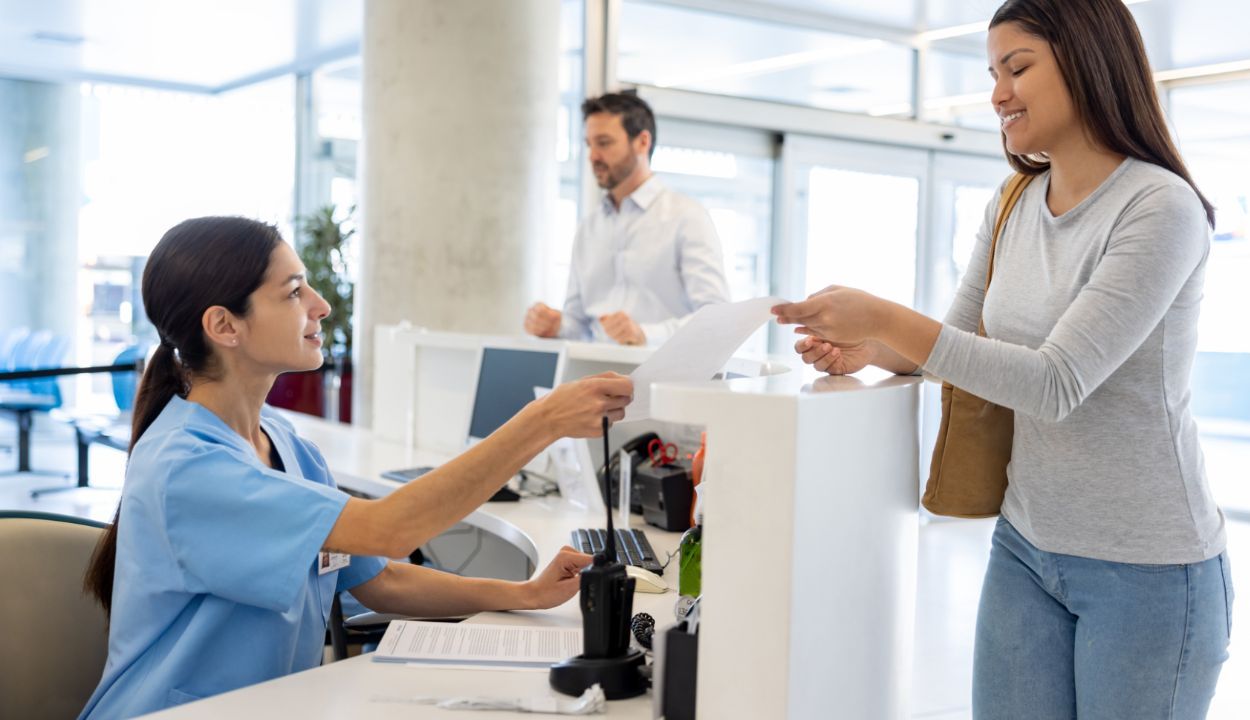 front counter receptionist handing visit summary to patient